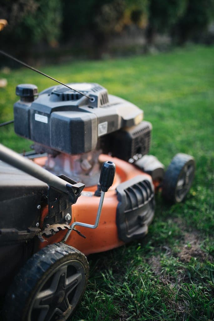 A lawn mower cutting grass in a suburban back yard